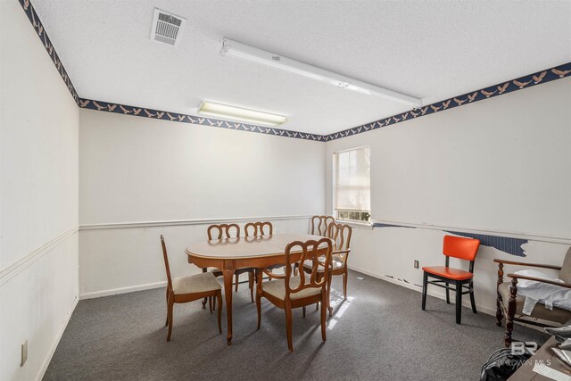 dining room with dark colored carpet and a textured ceiling