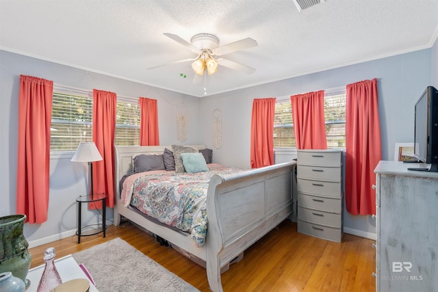 bedroom with crown molding, a textured ceiling, ceiling fan, and light hardwood / wood-style flooring