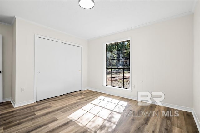 unfurnished bedroom with hardwood / wood-style flooring, a closet, and ornamental molding