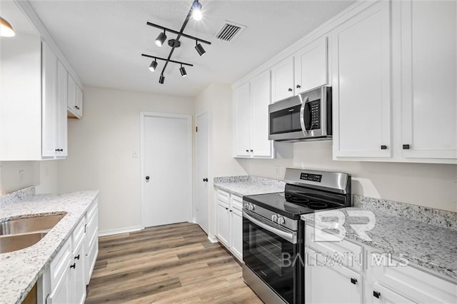 kitchen featuring white cabinets, stainless steel appliances, and track lighting