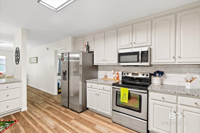 kitchen featuring light hardwood / wood-style flooring, decorative backsplash, light stone counters, white cabinetry, and stainless steel appliances