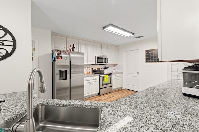 kitchen with light stone counters, sink, white cabinetry, and stainless steel appliances