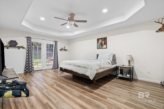 bedroom with access to exterior, ornamental molding, a tray ceiling, ceiling fan, and wood-type flooring