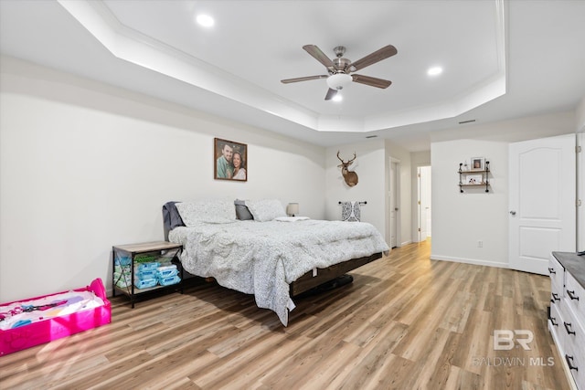 bedroom featuring a raised ceiling, ceiling fan, and light hardwood / wood-style flooring