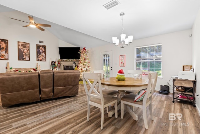 dining space with lofted ceiling, hardwood / wood-style floors, and ceiling fan with notable chandelier