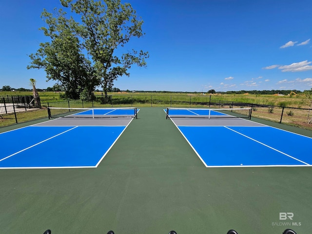 view of tennis court with a rural view