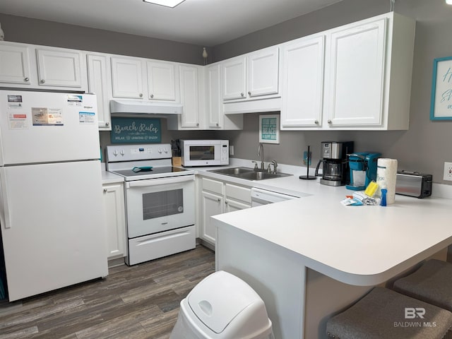 1117 W Lagoon Ave Unit 9, Gulf Shores, AL 36542 - kitchen featuring white appliances, a sink, under cabinet range hood, dark wood-type flooring, and a peninsula