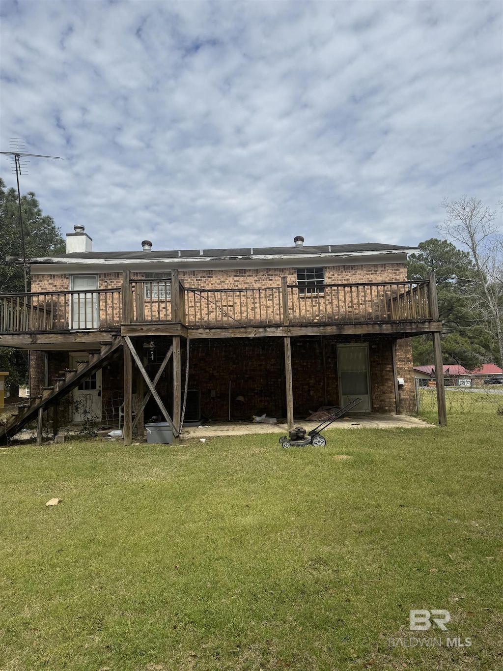 rear view of house featuring a lawn, a chimney, stairway, a wooden deck, and brick siding