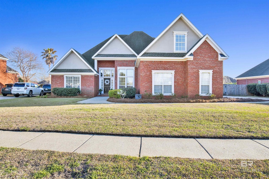 view of front of house featuring brick siding, fence, and a front yard