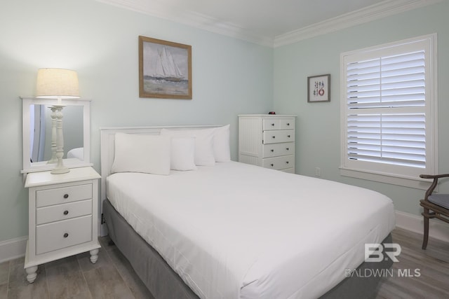 bedroom featuring baseboards, wood finished floors, and crown molding