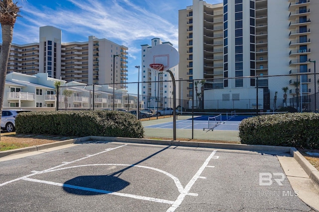 uncovered parking lot featuring community basketball court, fence, and a tennis court