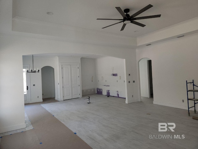 unfurnished living room with a raised ceiling and ceiling fan