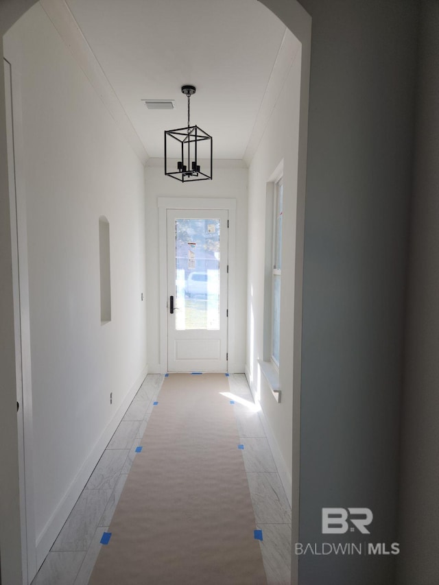 doorway featuring ornamental molding and a chandelier