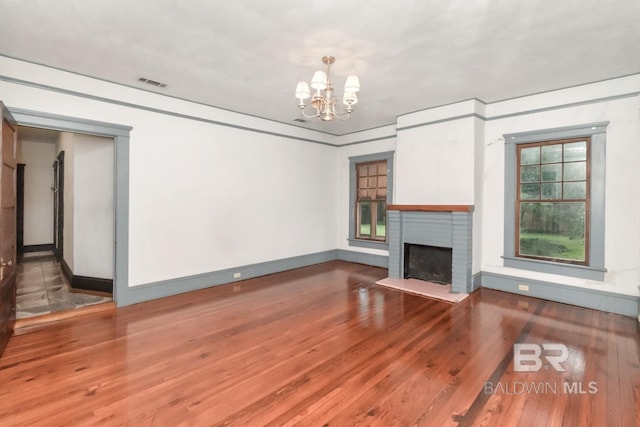 101 S Carlen St, Mobile, AL 36606 - unfurnished living room with a chandelier, wood finished floors, and a brick fireplace