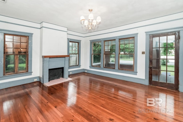 101 S Carlen St, Mobile, AL 36606 - unfurnished living room featuring wood-type flooring, a chandelier, and a brick fireplace