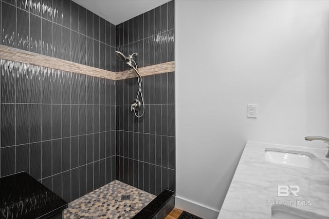 bathroom with a tile shower and vanity