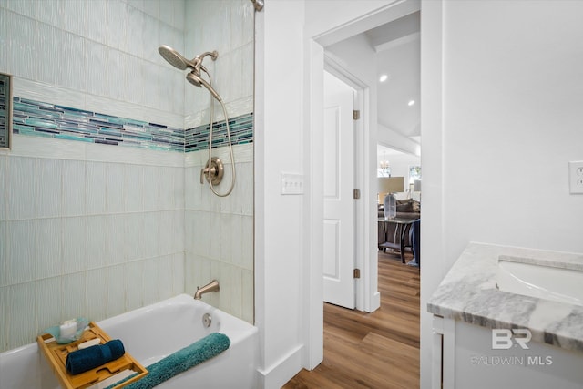 bathroom with wood-type flooring, vanity, and tiled shower / bath