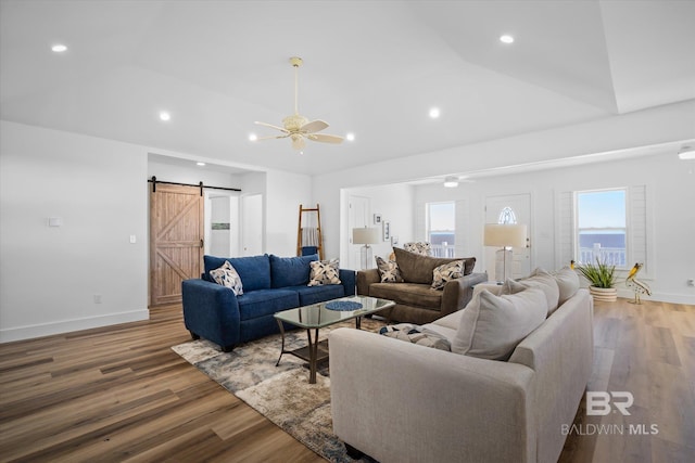 living room featuring a barn door, hardwood / wood-style flooring, ceiling fan, and lofted ceiling