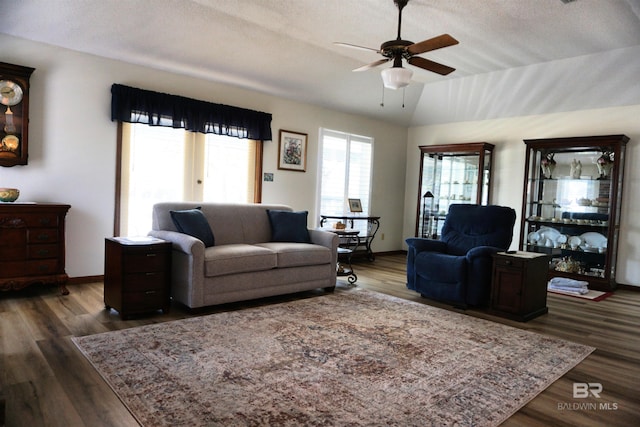 living room featuring lofted ceiling, dark wood-type flooring, and ceiling fan