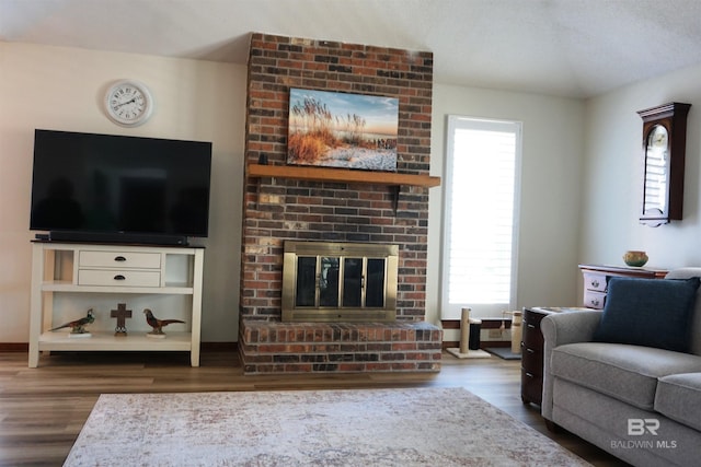 living room with a brick fireplace and wood-type flooring