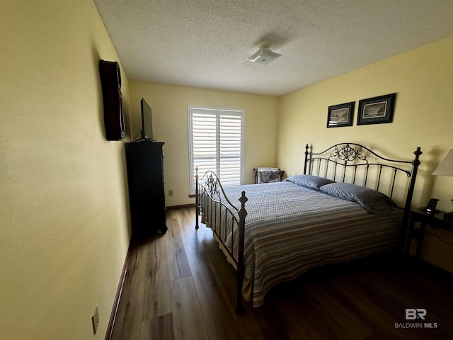 bedroom with dark wood-type flooring and a textured ceiling