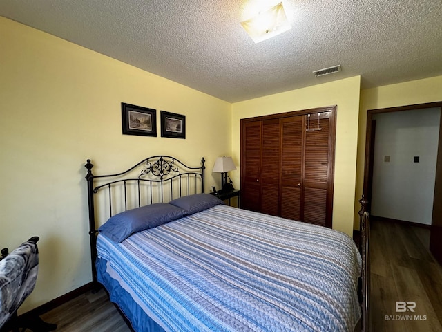 bedroom with dark wood-type flooring, a closet, and a textured ceiling