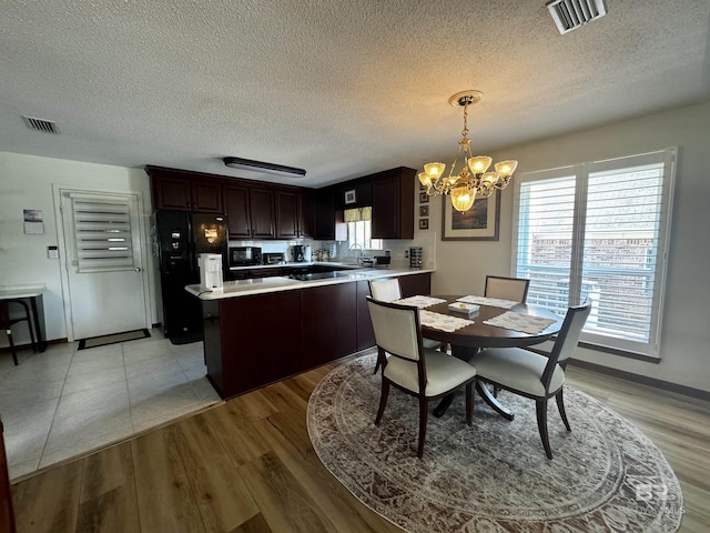 dining space with a textured ceiling, a notable chandelier, and light hardwood / wood-style floors