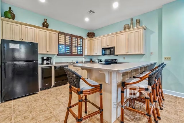 kitchen with kitchen peninsula, light tile floors, black appliances, and a breakfast bar