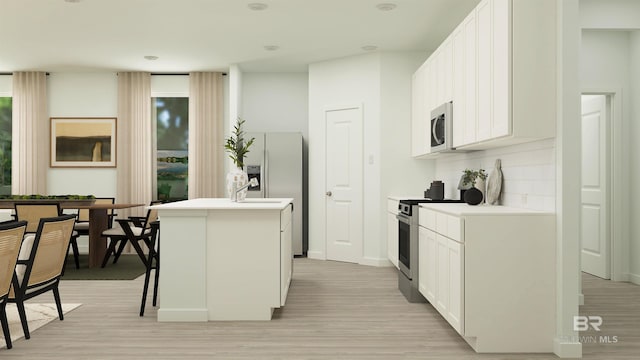 kitchen featuring stainless steel appliances, a kitchen island with sink, light wood-style flooring, backsplash, and white cabinets