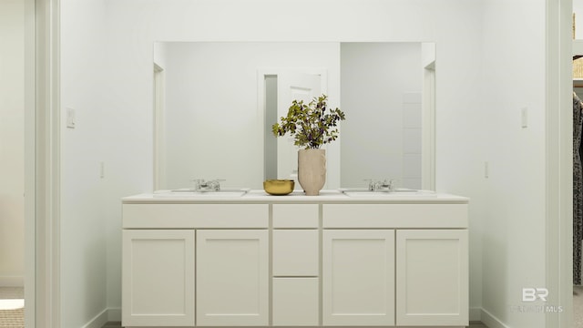 bathroom featuring baseboards, double vanity, and a sink