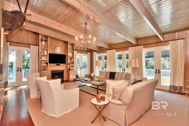 living room with french doors, a wealth of natural light, built in shelves, wooden walls, and beamed ceiling