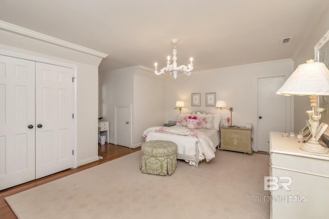 bedroom featuring hardwood / wood-style flooring, an inviting chandelier, a closet, and ornamental molding