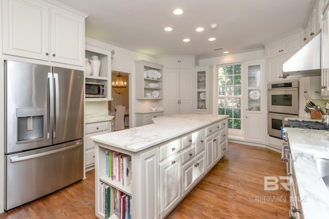 kitchen with white cabinets, a center island, light stone countertops, and stainless steel appliances