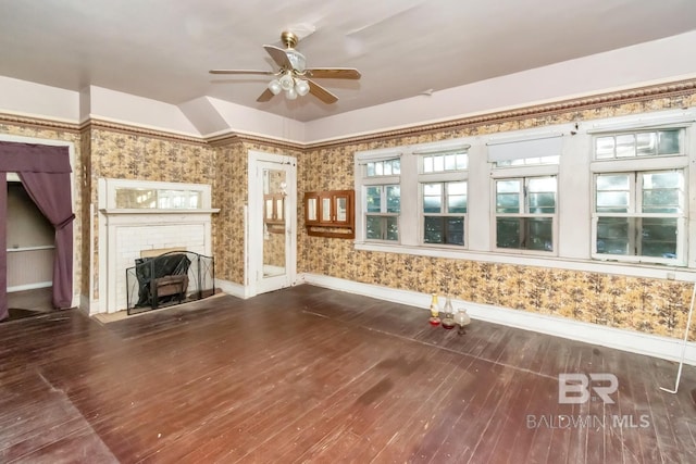 unfurnished living room with ceiling fan, hardwood / wood-style floors, and a brick fireplace