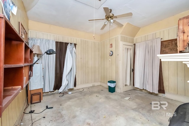 interior space featuring ceiling fan, wooden walls, and vaulted ceiling