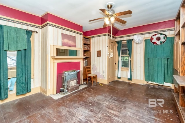 unfurnished living room with ceiling fan and a wood stove