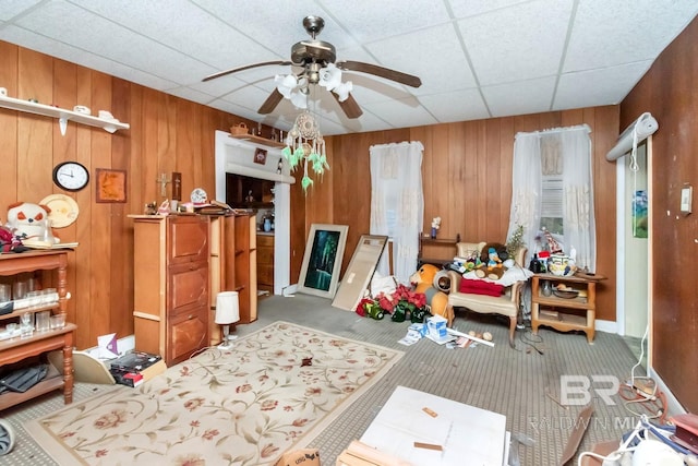 miscellaneous room with ceiling fan, carpet, wood walls, and a drop ceiling