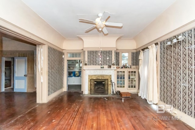 unfurnished living room with ceiling fan, a tiled fireplace, and hardwood / wood-style flooring