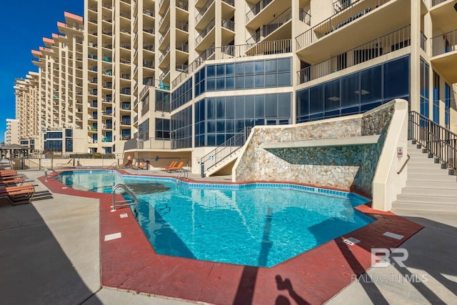 community pool with a patio area and stairs