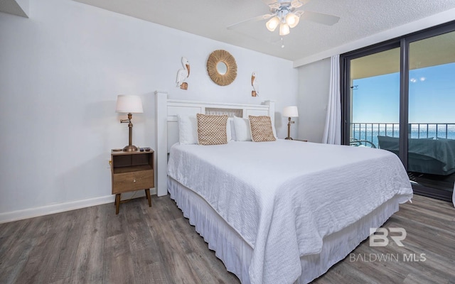 bedroom featuring a textured ceiling, access to outside, wood finished floors, and baseboards