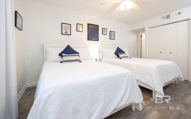 bedroom with a closet, visible vents, ceiling fan, wood finished floors, and baseboards