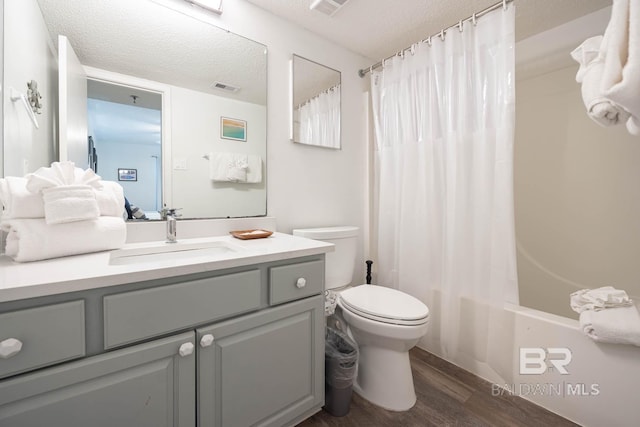 bathroom featuring a textured ceiling, toilet, wood finished floors, vanity, and visible vents