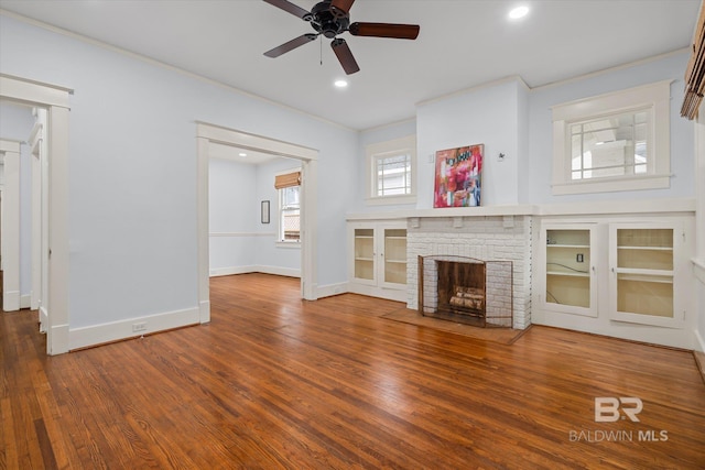 unfurnished living room featuring hardwood / wood-style floors, a fireplace, ornamental molding, and ceiling fan