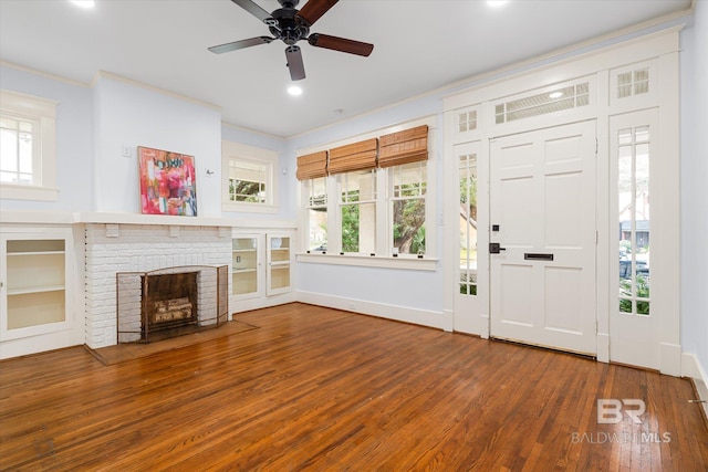 foyer entrance featuring ornamental molding, a brick fireplace, a healthy amount of sunlight, and hardwood / wood-style floors