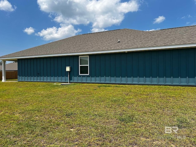 view of side of property featuring a yard, board and batten siding, and a shingled roof