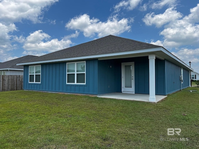 back of house featuring board and batten siding, fence, roof with shingles, a yard, and a patio