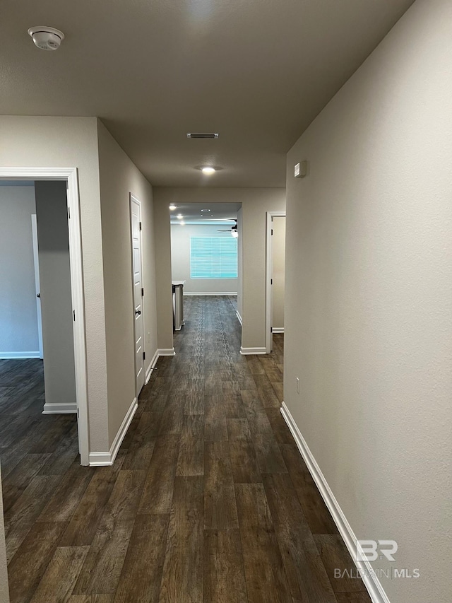 corridor featuring dark wood finished floors, visible vents, and baseboards