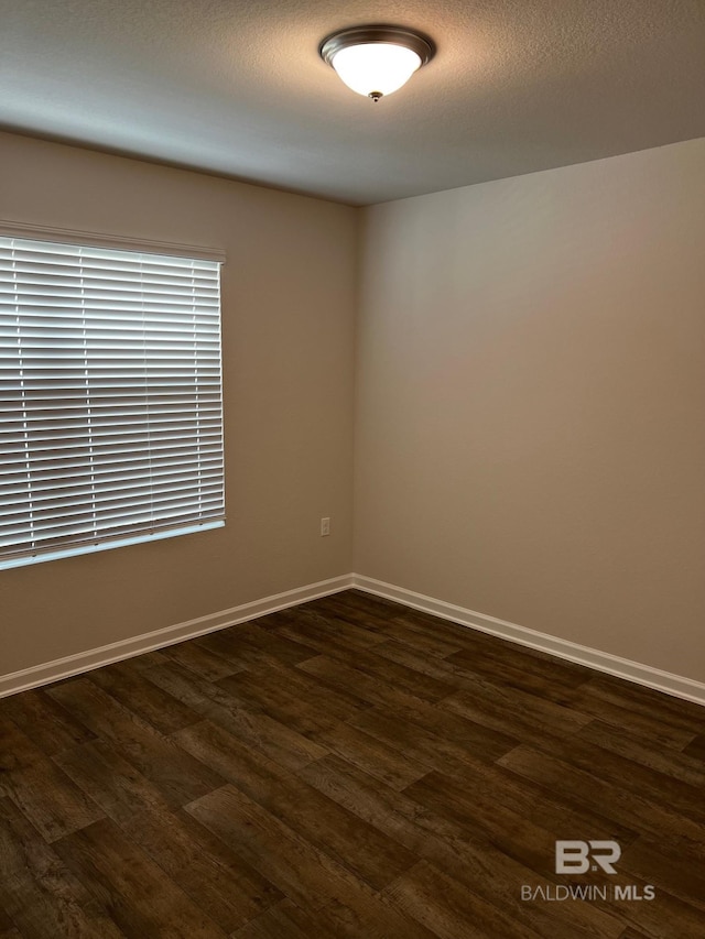 unfurnished room with dark wood finished floors, baseboards, and a textured ceiling