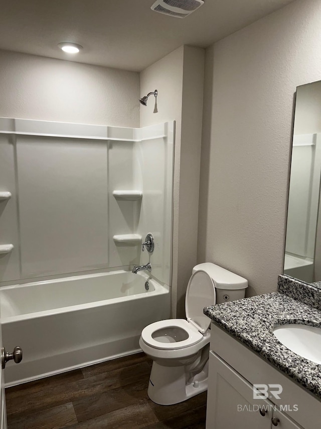 bathroom featuring visible vents, toilet, wood finished floors, shower / bath combination, and vanity