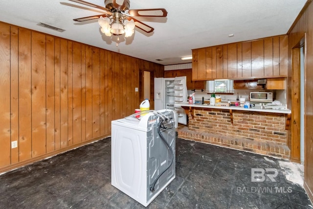3909 Blue Gill Cir, Mobile, AL 36619 - kitchen with white microwave, washer / dryer, ceiling fan, brown cabinetry, and wooden walls
